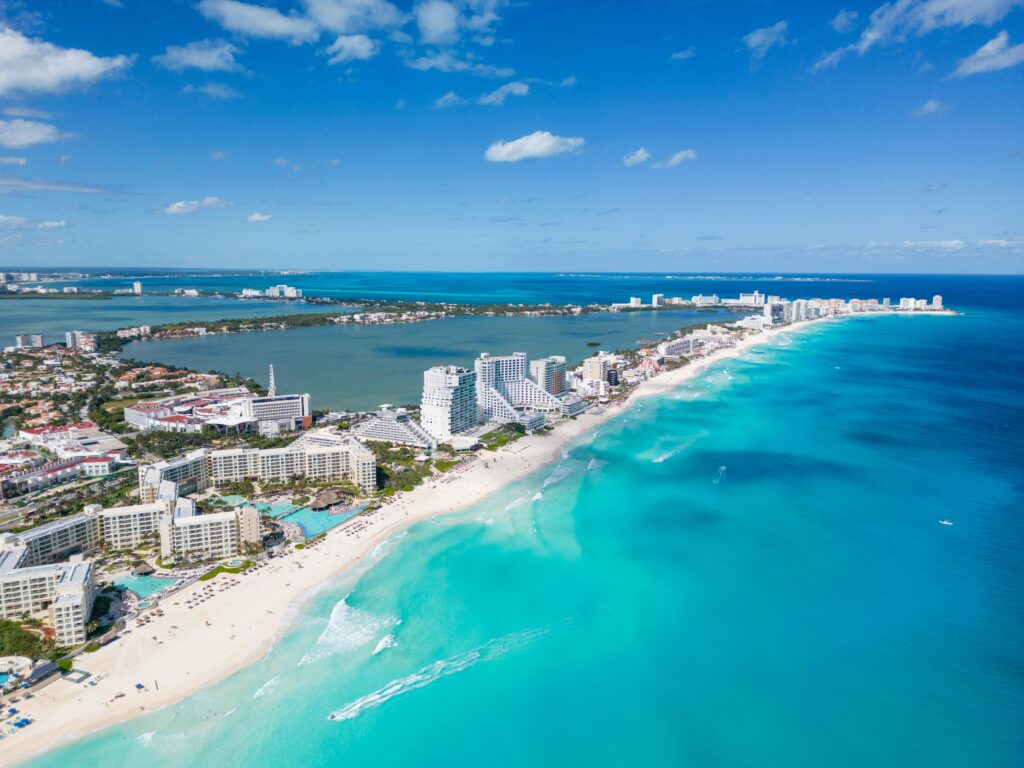 A breathtaking aerial view of Cancun, Mexico, showcasing its turquoise waters, white sandy beaches, and luxury resorts along the coastline.