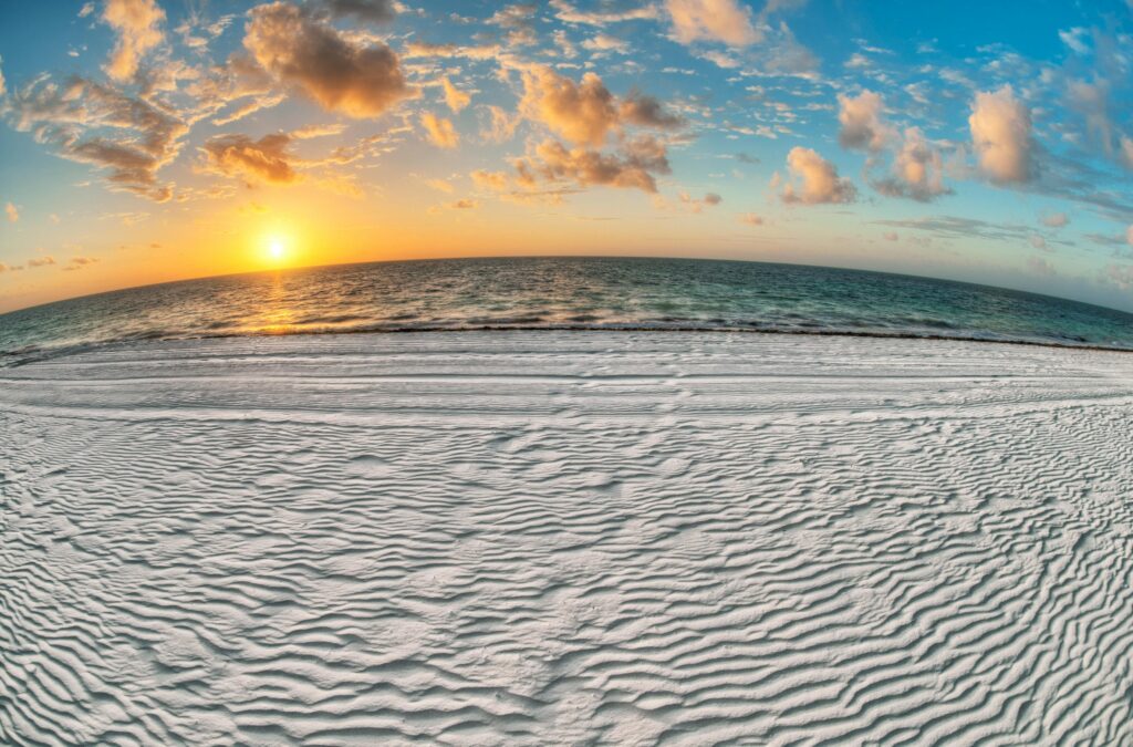 Breathtaking sunset over a pristine white-sand beach with gentle ocean waves, capturing the serene beauty of a tropical paradise.