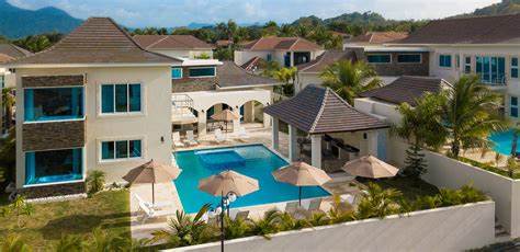 A luxurious 4-bedroom villa with a private pool, surrounded by tropical palm trees, featuring modern architecture with large windows, sun loungers, and shaded umbrellas at Royal Villas, Lifestyles Holidays Resorts in Cofresi, Puerto Plata, Dominican Republic.