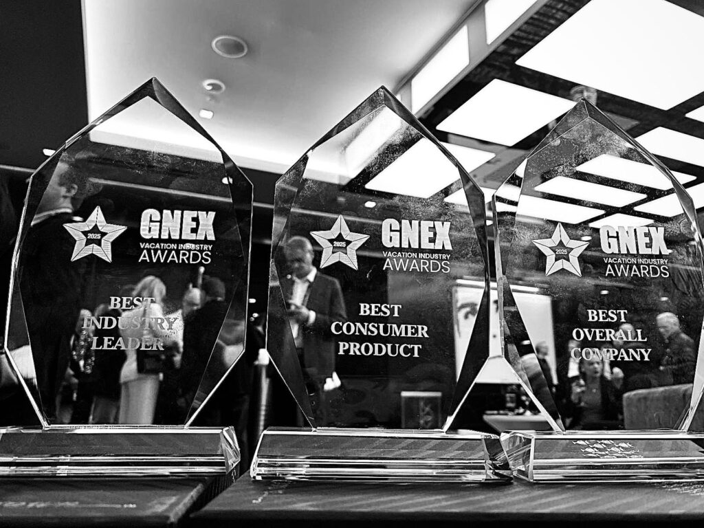 A close-up black-and-white image of three GNEX Vacation Industry Awards trophies displayed on a table. The awards recognize Best Industry Leader, Best Consumer Product, and Best Overall Company, reflecting excellence in the vacation ownership industry.