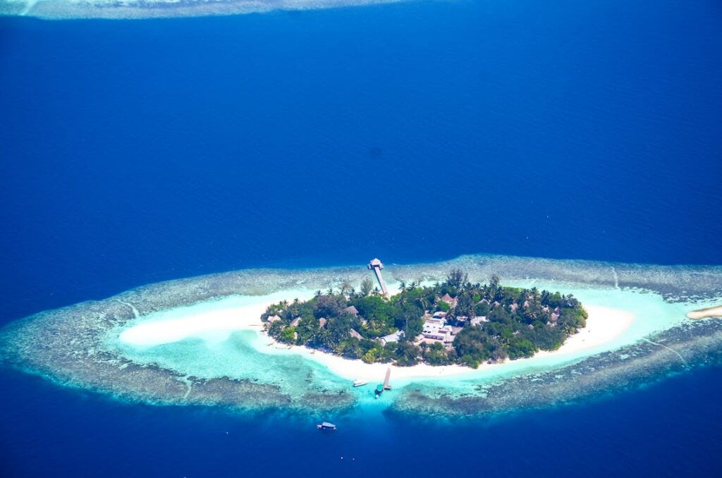 A stunning aerial view of a secluded island in the Maldives, surrounded by turquoise waters and vibrant coral reefs.