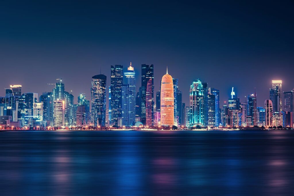 A breathtaking nighttime view of the Doha skyline, featuring illuminated skyscrapers reflecting over the calm waters of the Arabian Gulf.