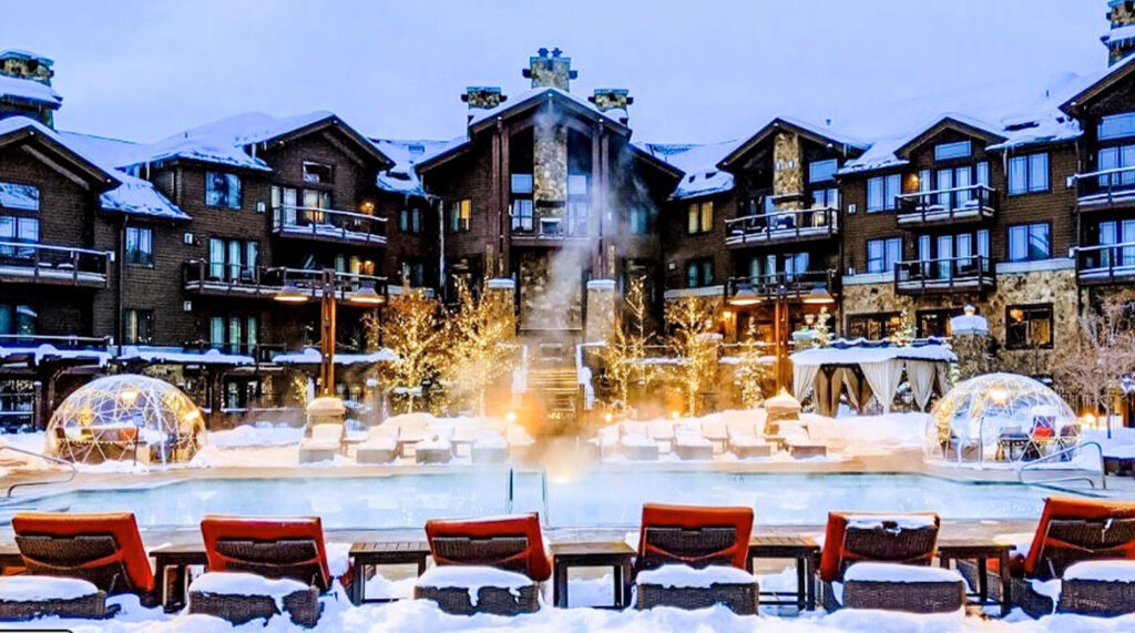 Luxury winter resort with a heated outdoor pool, igloo-style dining domes, and snow-covered surroundings at Waldorf Astoria Park City.