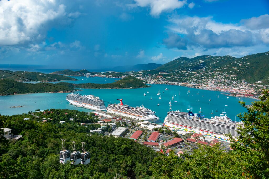 Aerial view of cruise ships docked in St. Thomas, U.S. Virgin Islands, surrounded by turquoise waters, green hills, and a busy harbor.
