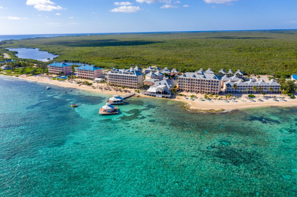 Aerial view of Morritt’s Tortuga Club resort in Grand Cayman, featuring beachfront suites, turquoise waters, and private dock areas.