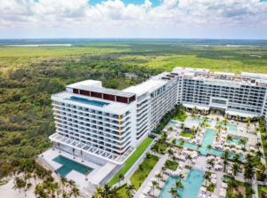Aerial view of Hotel Mousai Cancun showcasing luxury oceanfront architecture, multiple pools, and lush tropical surroundings.