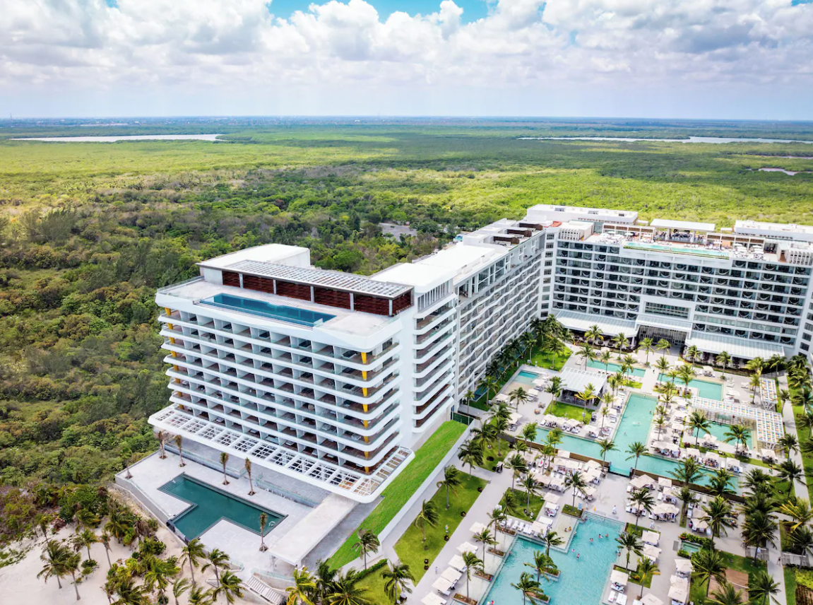Aerial view of Hotel Mousai Cancun showcasing luxury oceanfront architecture, multiple pools, and lush tropical surroundings.